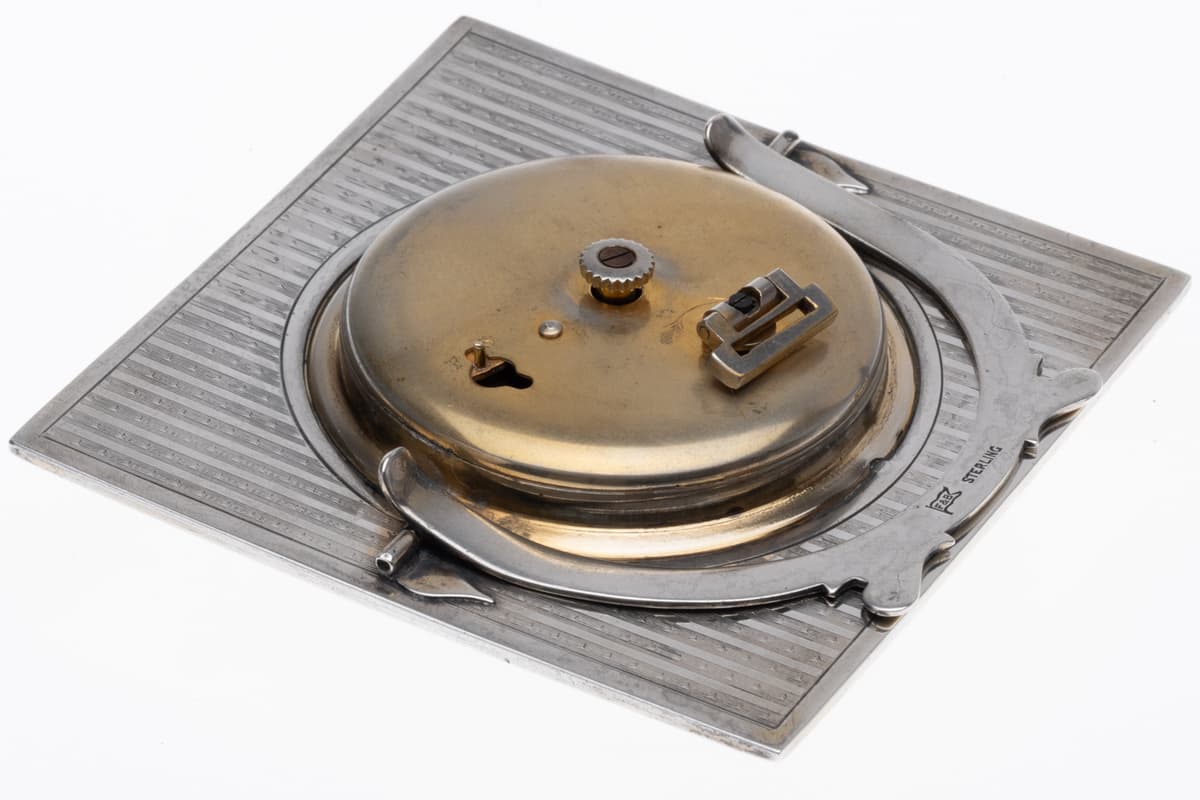 Angled rear view of Foster & Bailey sterling silver and enamel 8-day Swiss desk clock showing movement and stand.